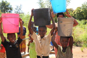 Kids in Malawi hold buckets of water on their heads