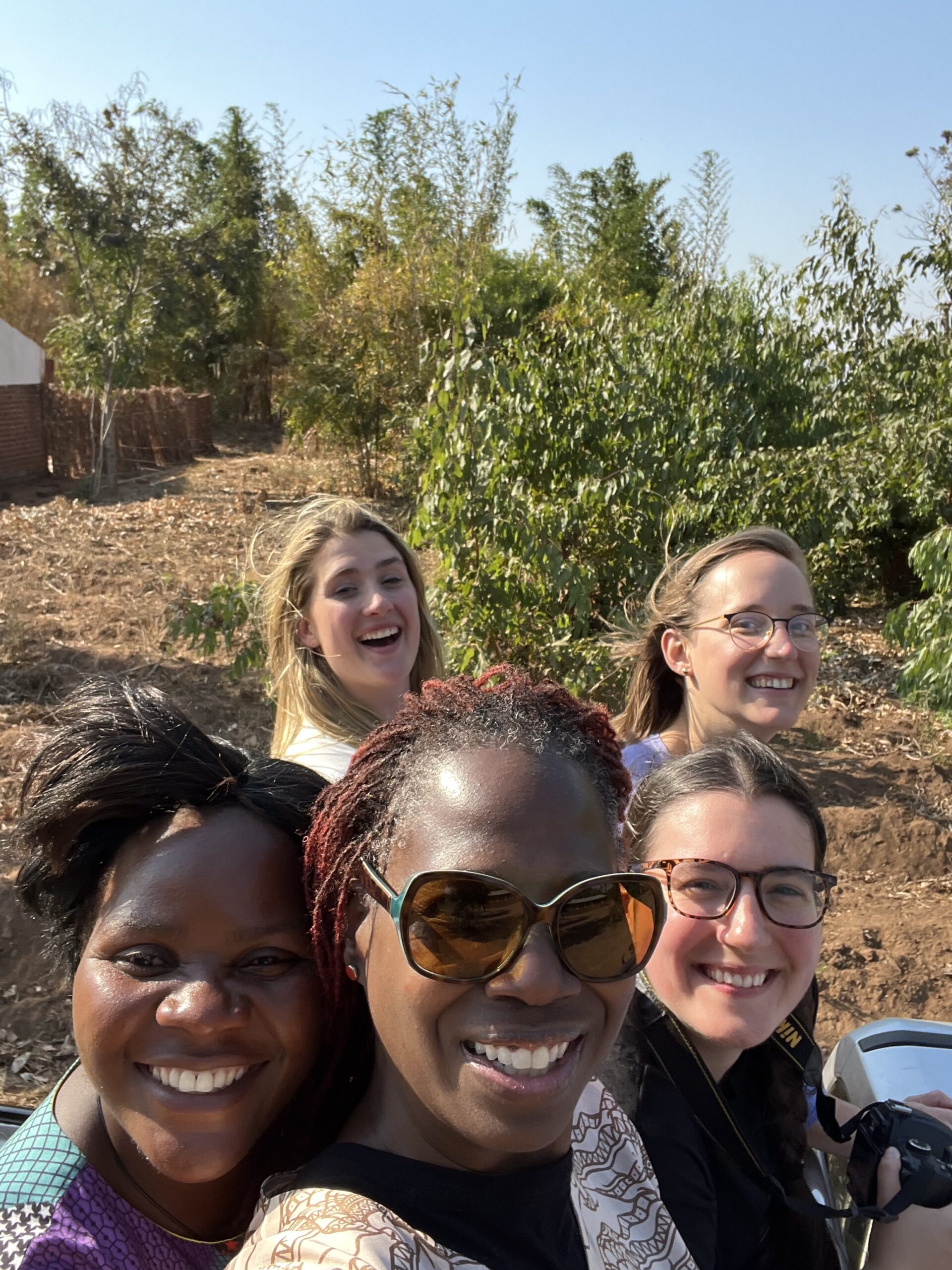 Kelsey (bottom-right) and 3 other visitors to Malawi ride in the back of a truck with Violet (bottom-left)